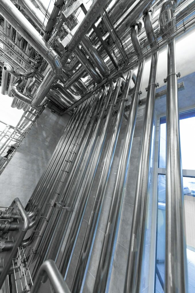 Steel pipelines and cables in factory interior as nuclear industry background concept